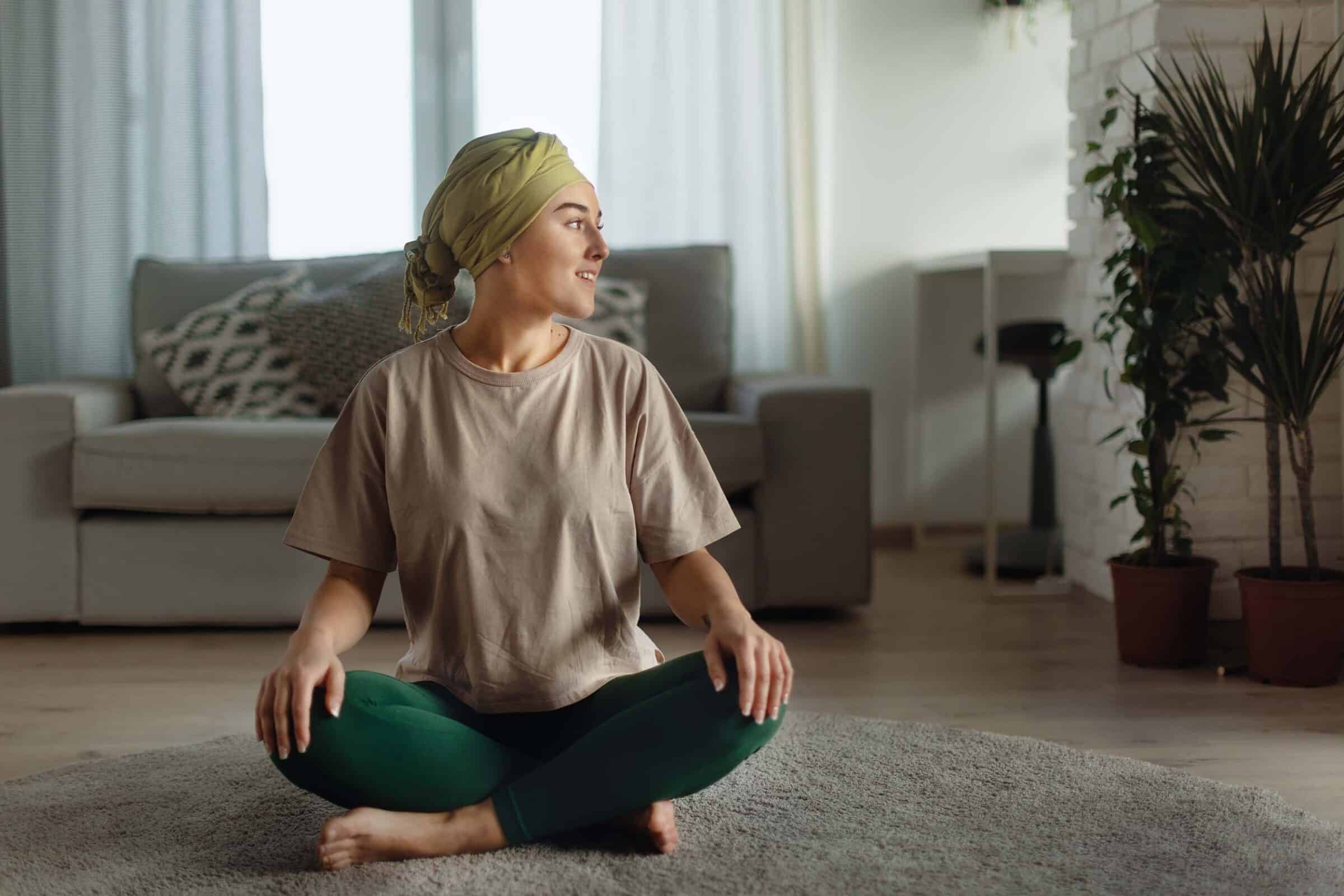Young woman doing yoga and meditating in her apartment living room.