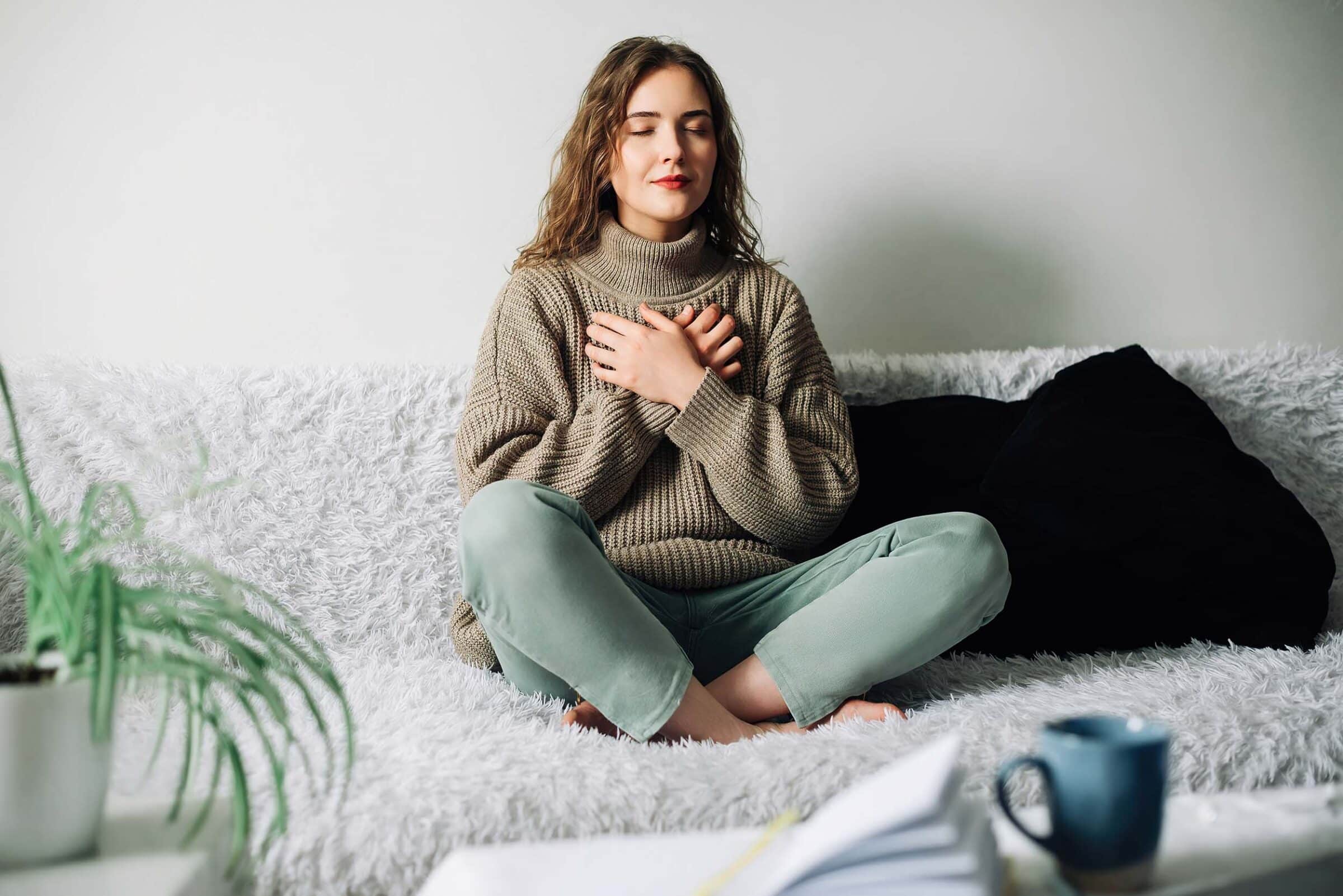 Woman practicing breathing exercises to reduce stress and anxiety on couch