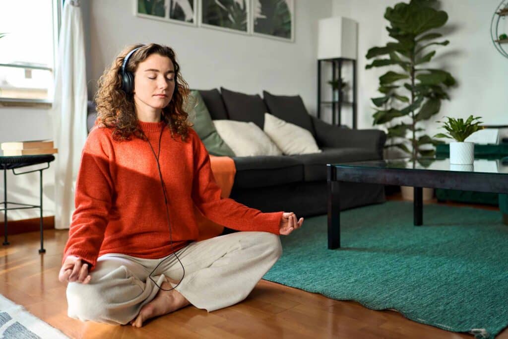 Mindful woman doing yoga meditation relaxing exercise for mental balance in apartment.